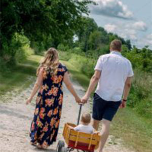 Family walking in a forest preserve. Photo of a mother and father pulling a child in a wagon on a forest preserve path.