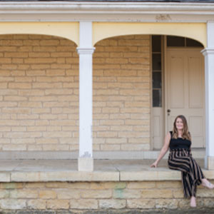 IABA Consultants owner Jessie Topalov sitting on a porch.