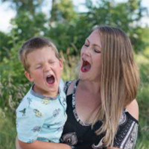 IABA Consultants owner Jessie Topalov playfully screaming with her son in a field.
