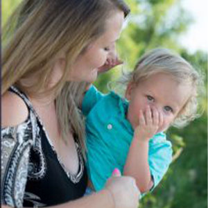 Photo of a mother holding her young son outside.