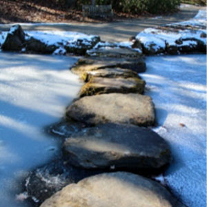 Sitting with Ourselves blog image. Photo of a makeshift stone bridge crossing a frozen river.