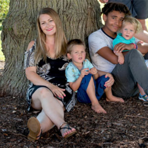 Finding Our Roots blog image. Photo of Jessie and her 3 boys sitting on the roots of a tree.