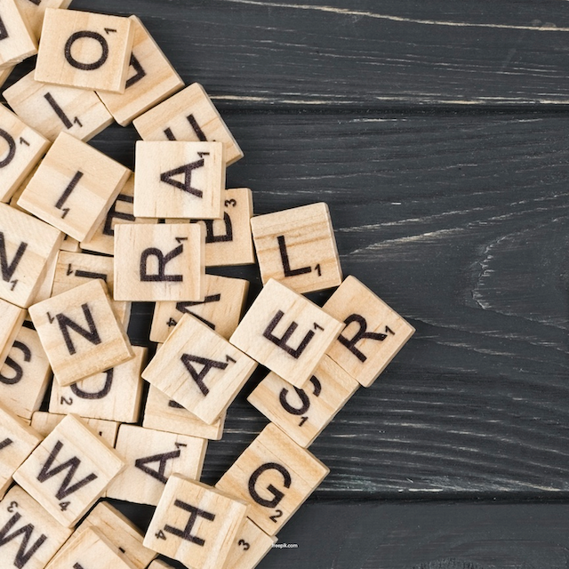 Autism isn't an Impairment, It's a Language Differences blog image. Photo of a bunch of scrabble tiles spilling onto a wooden table.